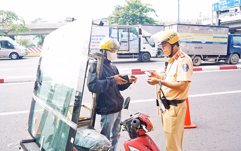 Đội Cảnh sát Giao thông Chợ Lớn nhắc nhở người tham gia giao thông trên tuyến đường Võ Văn Kiệt. (Ảnh THẾ ANH)
