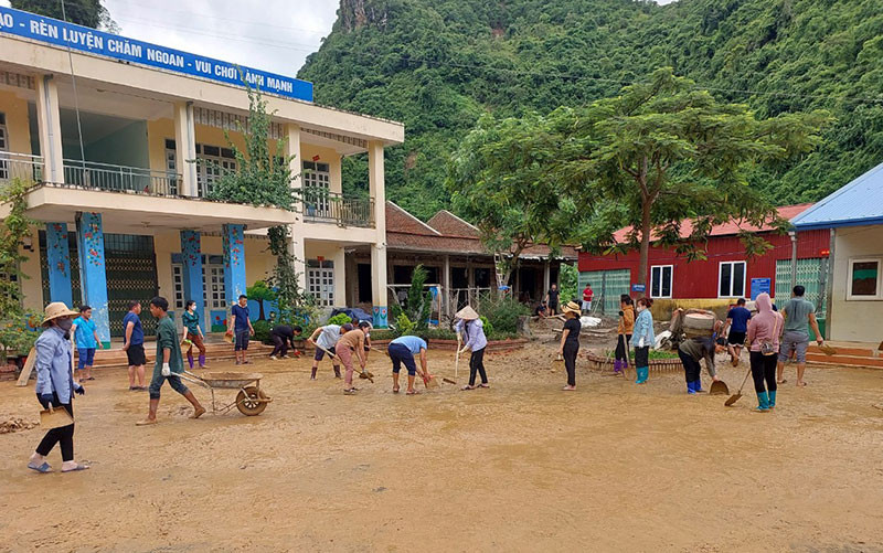 Các thầy, cô giáo và cha mẹ học sinh dọn dẹp sân trường bản Mùi II sau mưa lũ.