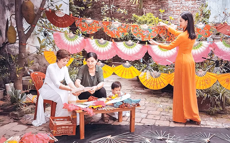 Nghệ nhân Nguyễn Thị Tuấn (áo sẫm) giới thiệu về nét đẹp quạt Chàng Sơn đến khách du lịch.