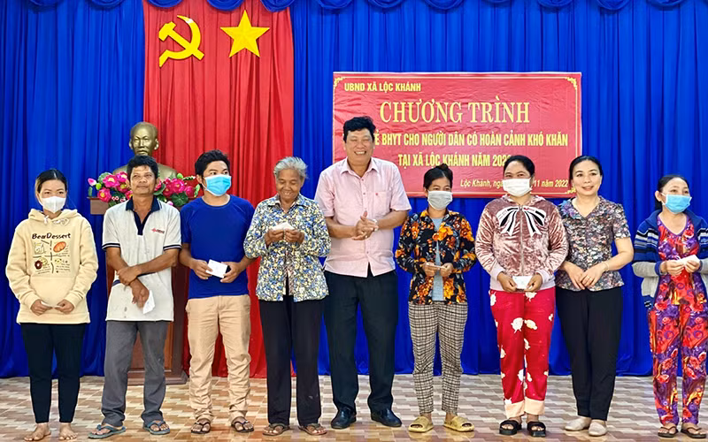 Đại diện Bảo hiểm xã hội tỉnh Bình Phước trao thẻ bảo hiểm y tế tặng người dân có hoàn cảnh khó khăn tại xã Lộc Khánh, huyện Lộc Ninh. (Ảnh THU CÚC)