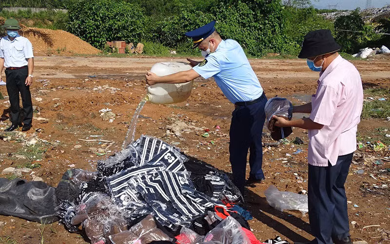 Lực lượng Quản lý thị trường tỉnh Quảng Trị tiêu hủy hàng hóa vi phạm. (Ảnh THU HÀ)