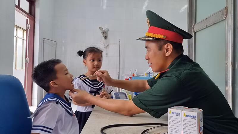 Đại úy, Bác sĩ, Thạc sĩ Lê Văn Quốc, Bệnh xá trưởng đảo Song Tử Tây thăm khám cho cháu Phan Gia Phát (4 tuổi).