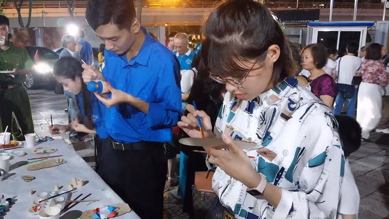 Khách mời trực tiếp trang trí búp bê Nga và tô màu tranh đĩa bằng gỗ.