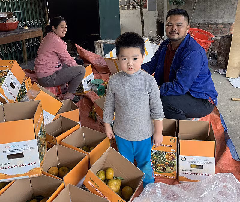 Vợ chồng anh Đại, chị Xuân và con trai đầu lòng bên những thùng quýt đặc sản Bắc Kạn.
