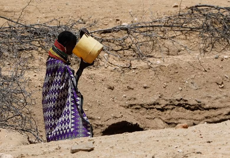 Một người phụ nữ uống nước trực tiếp từ một giếng mở được đào trên lòng sông khô ở làng Kakimat, hạt Turkana, Kenya, ngày 27/9. (Ảnh: REUTERS).