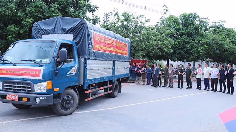 Người dân tỉnh Oudomxay (Lào) vẫy cờ tiễn đưa các liệt sĩ về đất Mẹ. (Ảnh: TRỊNH DŨNG)