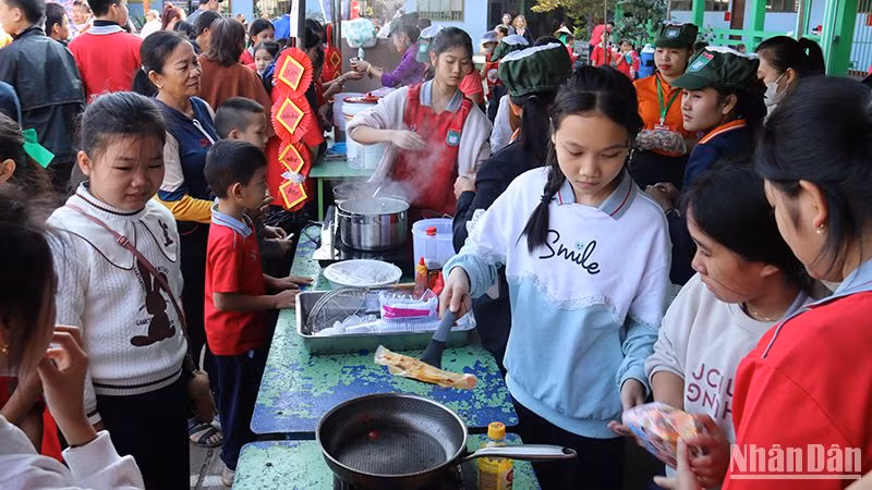 Các em học sinh hào hứng trải nghiệm và thưởng thức những món ăn truyền thống của Việt Nam tại hội chợ. (Ảnh: Hải Tiến)