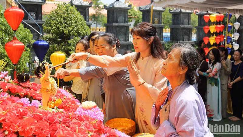 Chư tăng, phật tử cùng bà con kiều bào thực hiện nghi lễ tắm Phật. (Ảnh: Hải Tiến)