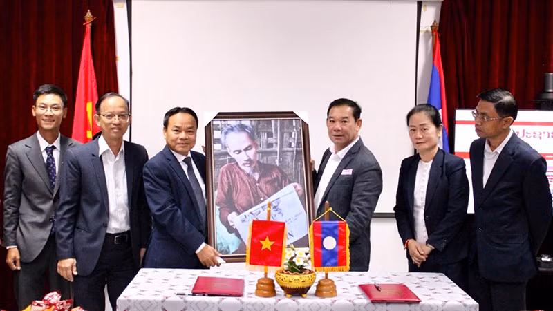 Đồng chí Đinh Như Hoan trao bức tranh Bác Hồ đọc Báo Nhân Dân tặng Ban Biên tập Báo Pasaxon. Ảnh: Hải Tiến