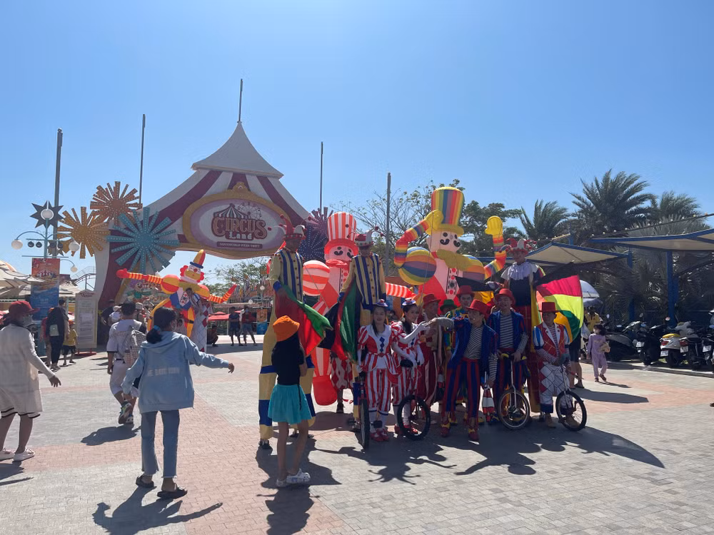 Du khách chụp hình với nghệ nhân biểu diễn đi cà kheo