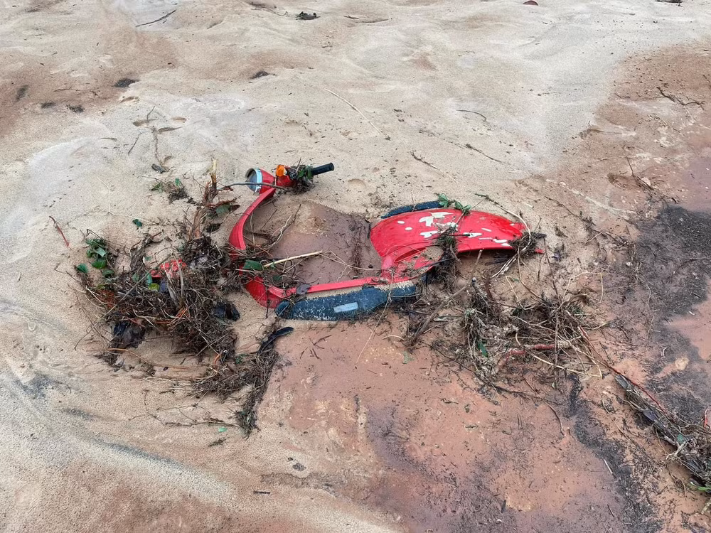 Một chiếc xe máy nằm dưới đống cát.