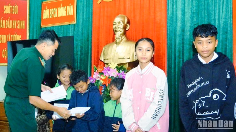 Đại diện Đồn Biên phòng Cửa khẩu Hồng Vân trao kinh phí hỗ trợ cho các em học sinh. (Ảnh: Võ Tiến).