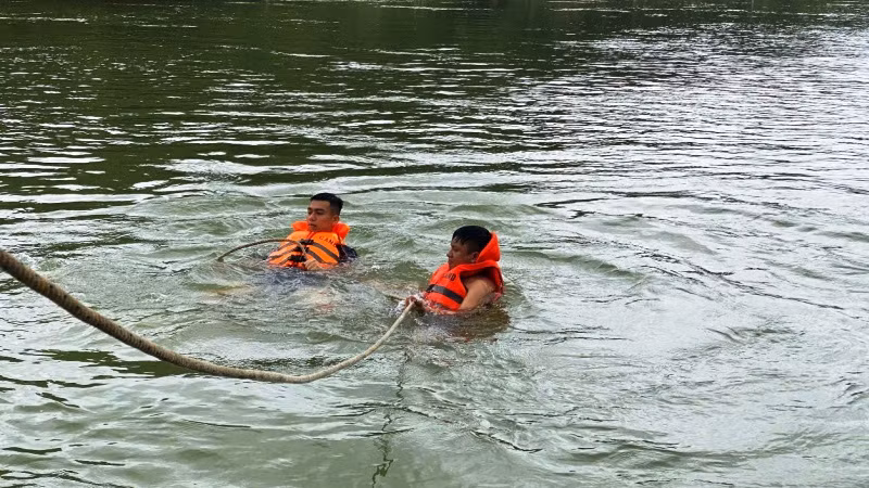 Lực lượng cứu nạn, cứu hộ móc dây vào xe bị nạn để kéo lên bờ.