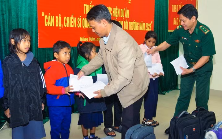Đại diện Đồn biên phòng cửa khẩu Hồng Vân và chính quyền địa phương trao kinh phí hỗ trợ cho các em học sinh. (Ảnh: Hồng Minh).