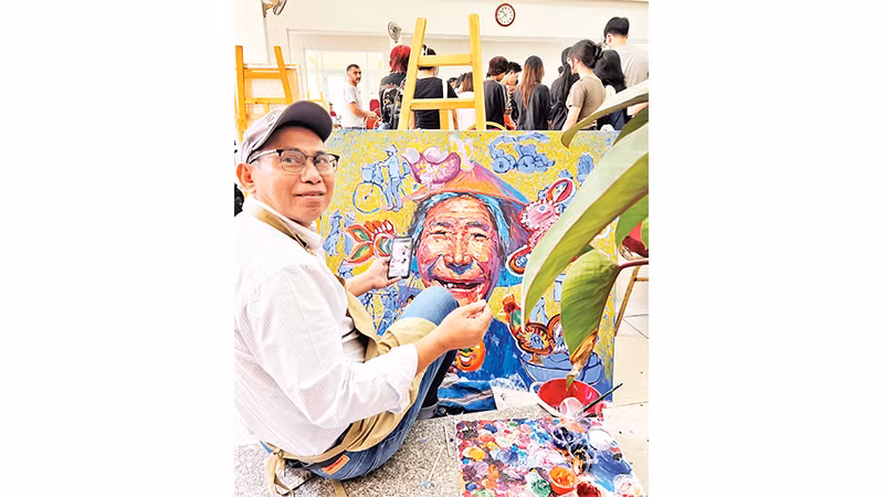 Họa sĩ người Myanmar Myoe Kyaw bên bức tranh của ông tại workshop Hanoi Art Connecting năm 2024. Ảnh: An Trung