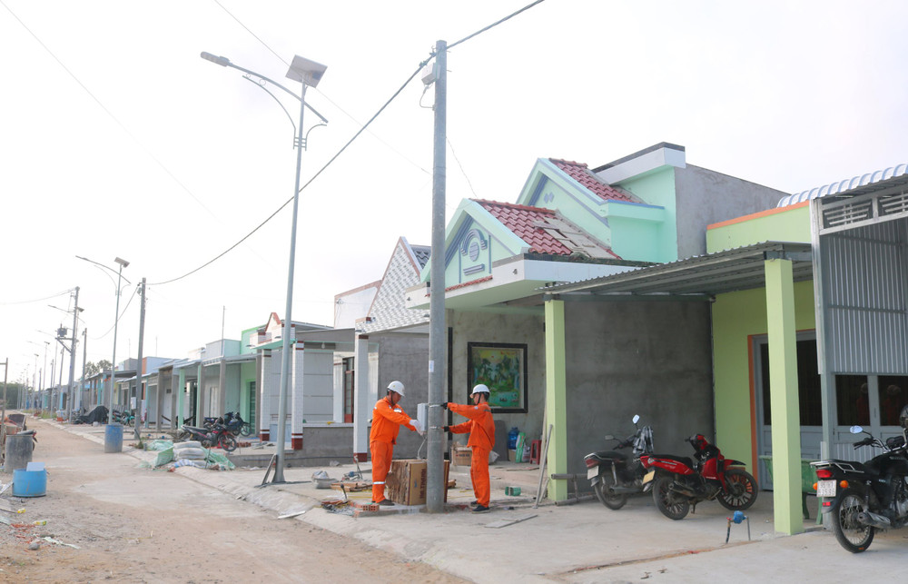 Nhân viên điện lực huyện Duyên Hải lắp đặt đồng hồ điện cho hộ gia đình anh Lê Tấn Tài, khu tái định cư ấp Hồ Thùng, xã Đông Hải, huyện Duyên Hải. (Ảnh MINH KHỞI)