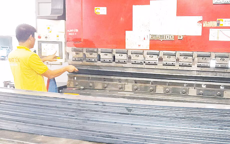 Kỹ sư đang vận hành máy chấn tôn để sản xuất máng cáp điện tại nhà máy của Công ty TNHH Thiết bị điện Phát Tiến (Quận 12). 