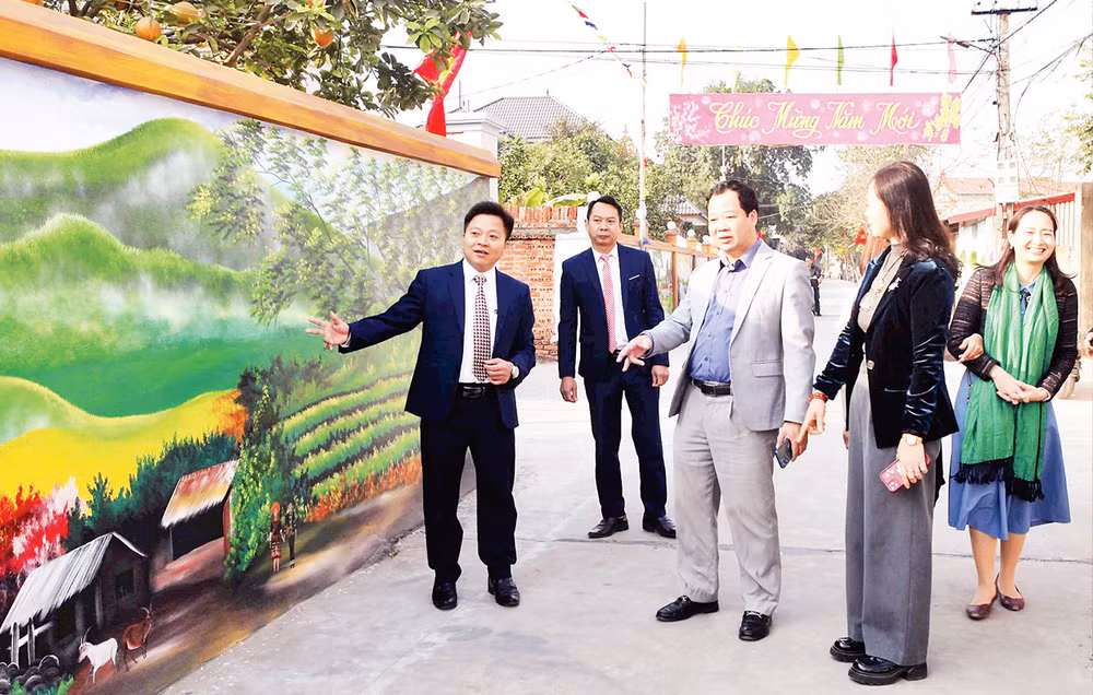 Thành viên đoàn thẩm định nông thôn mới thành phố Hà Nội thăm tuyến đường kiểu mẫu tại thôn Đan Tảo, xã Tân Minh, huyện Sóc Sơn. (Ảnh Ngọc Lan) 