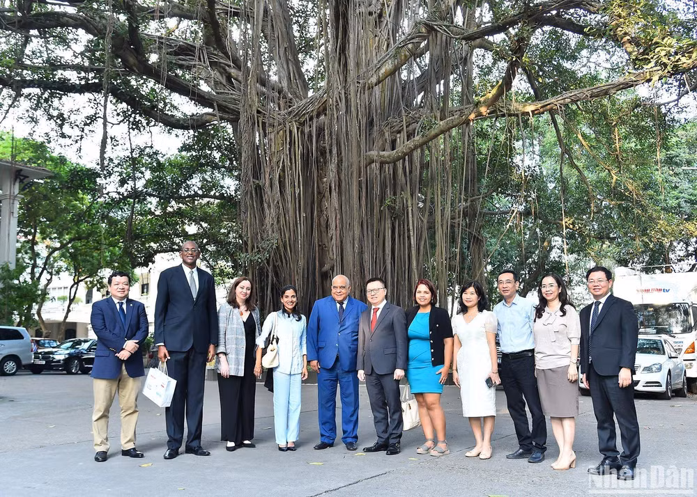 Tổng Biên tập Báo Nhân Dân Lê Quốc Minh và Phó Tổng Biên tập Báo Granma Arlin Alberty Loforte cùng cán bộ của hai cơ quan báo chí chụp ảnh lưu niệm bên gốc cây đa trong khuôn viên Báo Nhân Dân. (Ảnh: THỦY NGUYÊN)