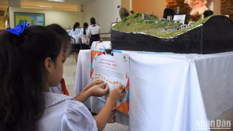 Các em học sinh dán biểu trưng bình chọn cho mô hình của sinh viên Trường đại học Bách Khoa - Đại học Đà Nẵng tham gia cuộc thi làm các công trình kiến trúc tiêu biểu tại thành phố Đà Nẵng. (Ảnh: ANH ĐÀO)
