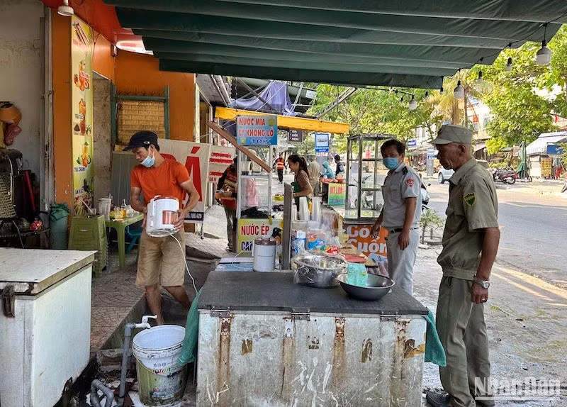 Lực lượng quy tắc đô thị phường Nại Hiên Đông tuyên truyền, vận động người dân thu dọn vật dụng kinh doanh, để tiến hành kẻ vạch vỉa hè. Ảnh: ANH ĐÀO