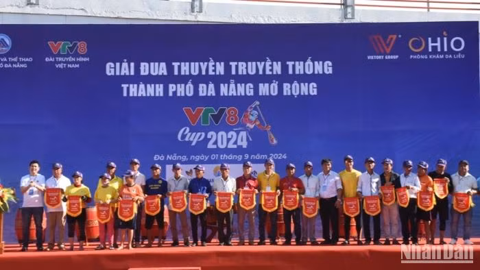 Ban tổ chức trao cờ lưu niệm cho các đội tham gia đua thuyền. (Ảnh: ANH ĐÀO)