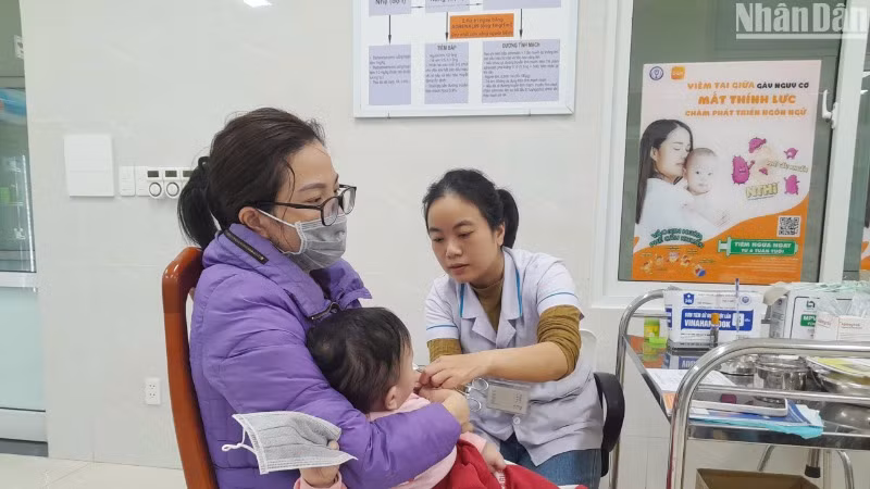 Người dân đưa con đến Trung tâm kiểm soát bệnh tật thành phố Đà Nẵng tiêm tiêm vắc-xin phòng cúm mùa. (Ảnh: L.HÙNG)