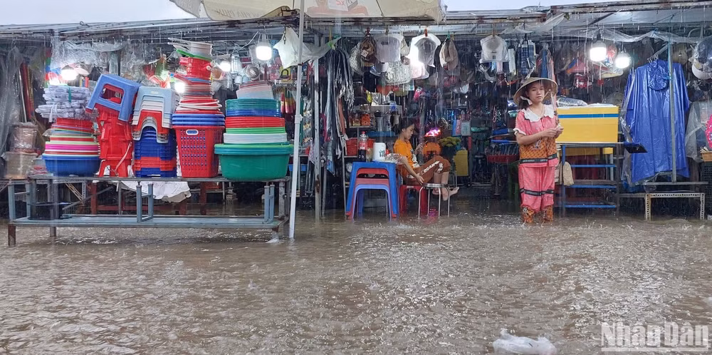 Tiểu thương chợ Thanh Vinh lội bì bõm trong nước ngập sâu để kê cao hàng hóa.