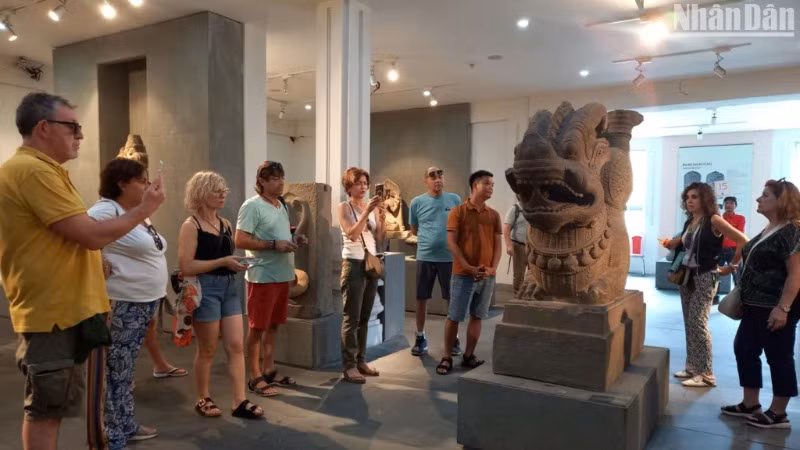 Du khách tham quan Bảo vật Quốc gia Tượng Rồng Tháp Mẫm tại Bảo tàng Điêu khắc Chăm. (Ảnh: ANH ĐÀO)