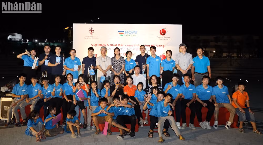 Ông Taketoshi Nagaoka, nhạc trưởng Honna Tetsuji và các nghệ sĩ của Dàn nhạc giao hưởng Việt Nam và các em học sinh Trường Hy Vọng. (Ảnh: ANH ĐÀO)