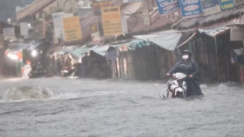 Người dân thận trọng dắt xe máy qua khu vực có nắp cống bị bung ra do mưa lớn (ngày 10/5) tại chợ Thủ Đức. (Ảnh: THẾ ANH)