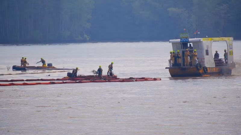 Nhân viên ứng phó sự cố môi trường quây phao ngăn dầu tràn ra ngoài.