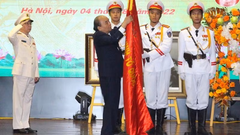 Chủ tịch nước Nguyễn Xuân Phúc gắn danh hiệu Anh hùng Lực lượng vũ trang nhân dân lên Cờ truyền thống của đơn vị. (Ảnh: Báo CAND)