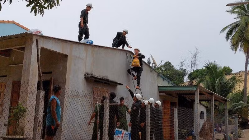 Lực lượng Cảnh sát cơ động giúp người dân thôn Nhơn Hội, xã Xuân Cảnh, thị xã Sông Cầu dùng bao cát gia cố mái che chống bão số 4.