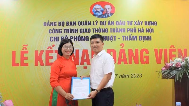 Bí thư Chi bộ Phòng Kỹ thuật-Thẩm định (Ban Quản lý dự án đầu tư xây dựng công trình giao thông thành phố Hà Nội) trao Quyết định kết nạp đảng cho đồng chí Bùi Thị Phương Ngọc. Ảnh: Linh Nguyễn