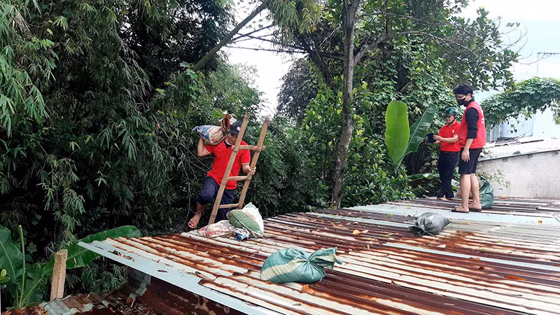Tình nguyện viên Chữ thập đỏ giúp người dân chằng mái nhà.