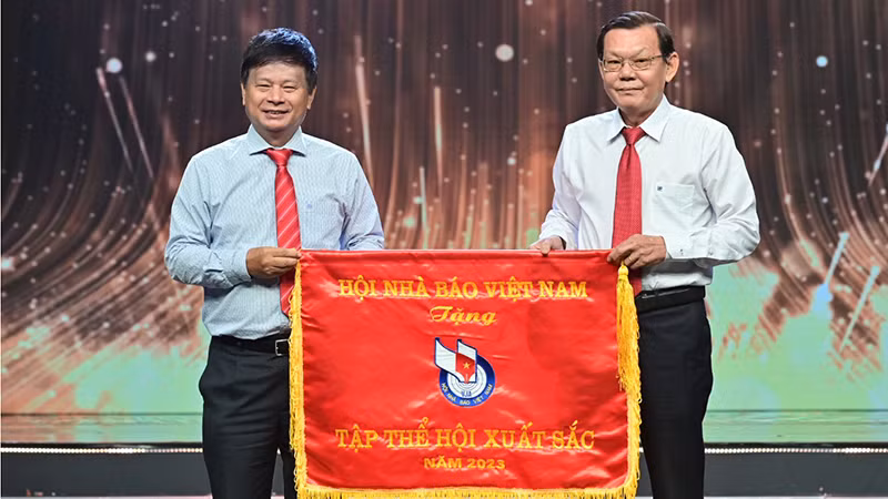 Ông Trần Trọng Dũng (bìa trái), Phó Chủ tịch Hội Nhà báo Việt Nam, phụ trách phía nam trao Cờ thi đua tập thể xuất sắc năm 2023 cho Hội Nhà báo Thành phố Hồ Chí Minh. (Ảnh: Quốc Thanh)