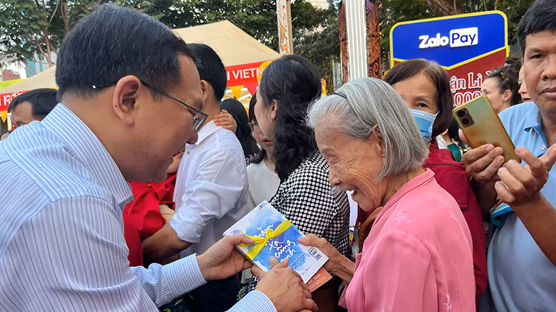 Ông Lâm Đình Thắng, Giám đốc Sở Thông tin và Truyền thông Thành phố Hồ Chí Minh lì xì sách Tết cho du khách.