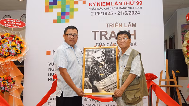 Nhà báo Huỳnh Dũng Nhân tặng Báo Nhân Dân bức tranh Bác Hồ đọc Báo Nhân Dân. (Ảnh: Thế Anh)