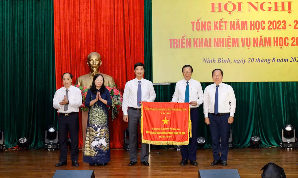 Thừa ủy quyền của Thủ tướng Chính phủ, Thứ trưởng Giáo dục và Đào tạo Phạm Ngọc Thưởng trao tặng Cờ thi đua của Chính phủ. (Ảnh: Minh Quang)