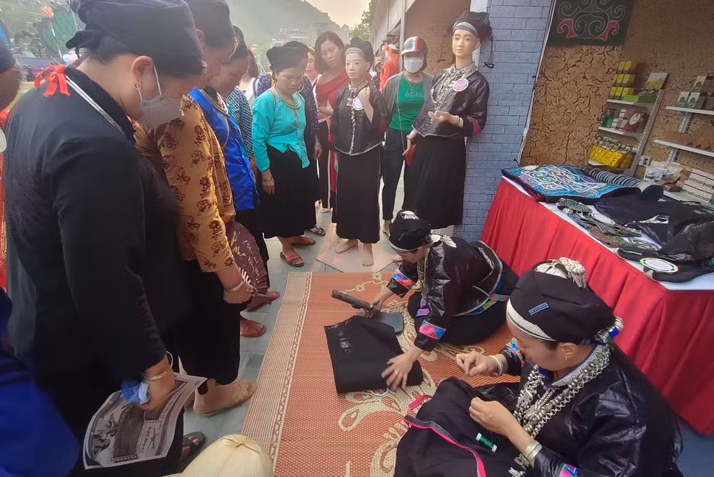 Người dân thành phố Hà Giang xem các nghệ nhân người dân tộc Nùng, huyện Xín Mần thêu hoa văn trên vải thổ cẩm.