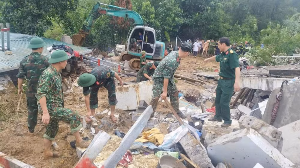 Lực lượng chức năng hỗ trợ người dân khắc phục hậu quả do sạt lở đất.