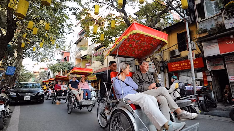 Du khách nước ngoài sử dụng xích-lô thưởng ngoạn nét đẹp cổ kính của Phố cổ Hà Nội. (Ảnh: TTXVN)
