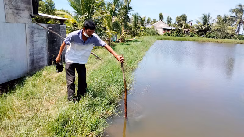 Ông Đặng Văn Đa đo mực nước nơi 2 đứa cháu nội bị đuối nước.