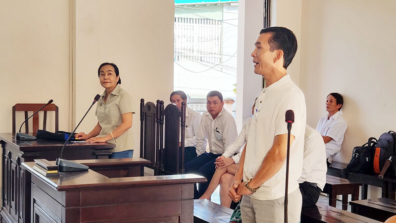 Ông L. M. T (đứng bên phải), con của bà T. T. S và ông L. T. H - người có quyền lợi và nghĩa vụ liên quan đến vụ án và bà Nguyễn Thu Hà (đứng bên trái) tại phiên tòa, sáng 25/10.