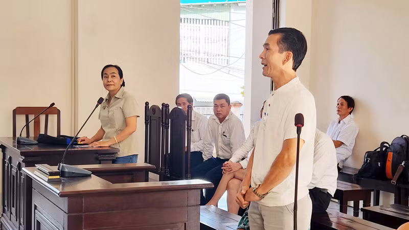 Ông L. M. T (đứng bên phải), con của bà T. T. S và ông L. T. H - người có quyền lợi và nghĩa vụ liên quan đến vụ án và bà Nguyễn Thu Hà (đứng bên trái) tại phiên tòa, sáng 25/10.