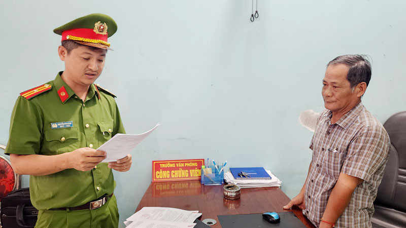 Điều tra viên đọc lệnh bắt tạm giam ông Trần Thiện Thi. (Ảnh: Văn Vũ)
