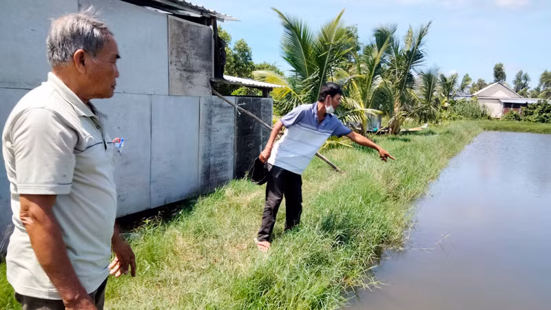 Ông Đặng Văn Đa (bên phải) chỉ nơi 2 cháu nội bị đuối nước tử vong.