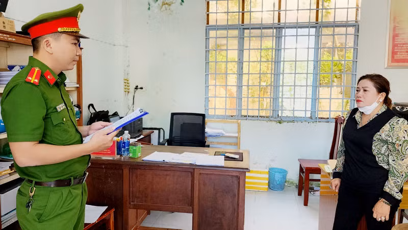 Cán bộ điều tra tống đạt quyết định khởi tố bị can đối với Võ Thị Thanh Nga. (Ảnh: VĂN VŨ)