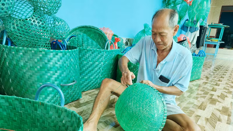 Ông Nguyễn Văn Lẹ đan rổ dùng để rửa cá, thịt.